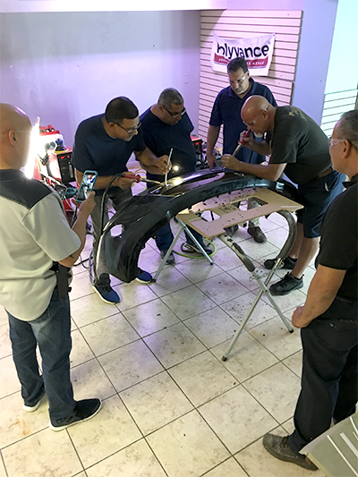 A group of men watching two other men use the nitrogen plastic welder.