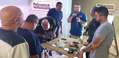 A group of men watching John explain welding.