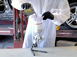 A man filtering Bumper and Cladding Coat Adhesion Primer into his spray gun.
